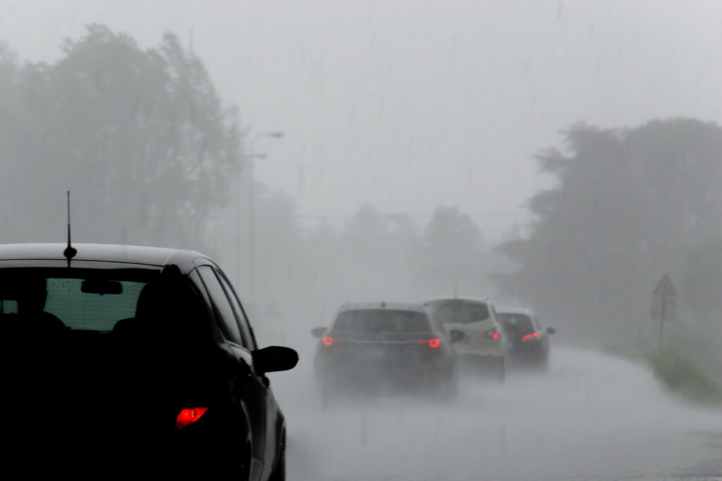 photo of the strong storm with heavy rain on the road with poor visibility of cars.